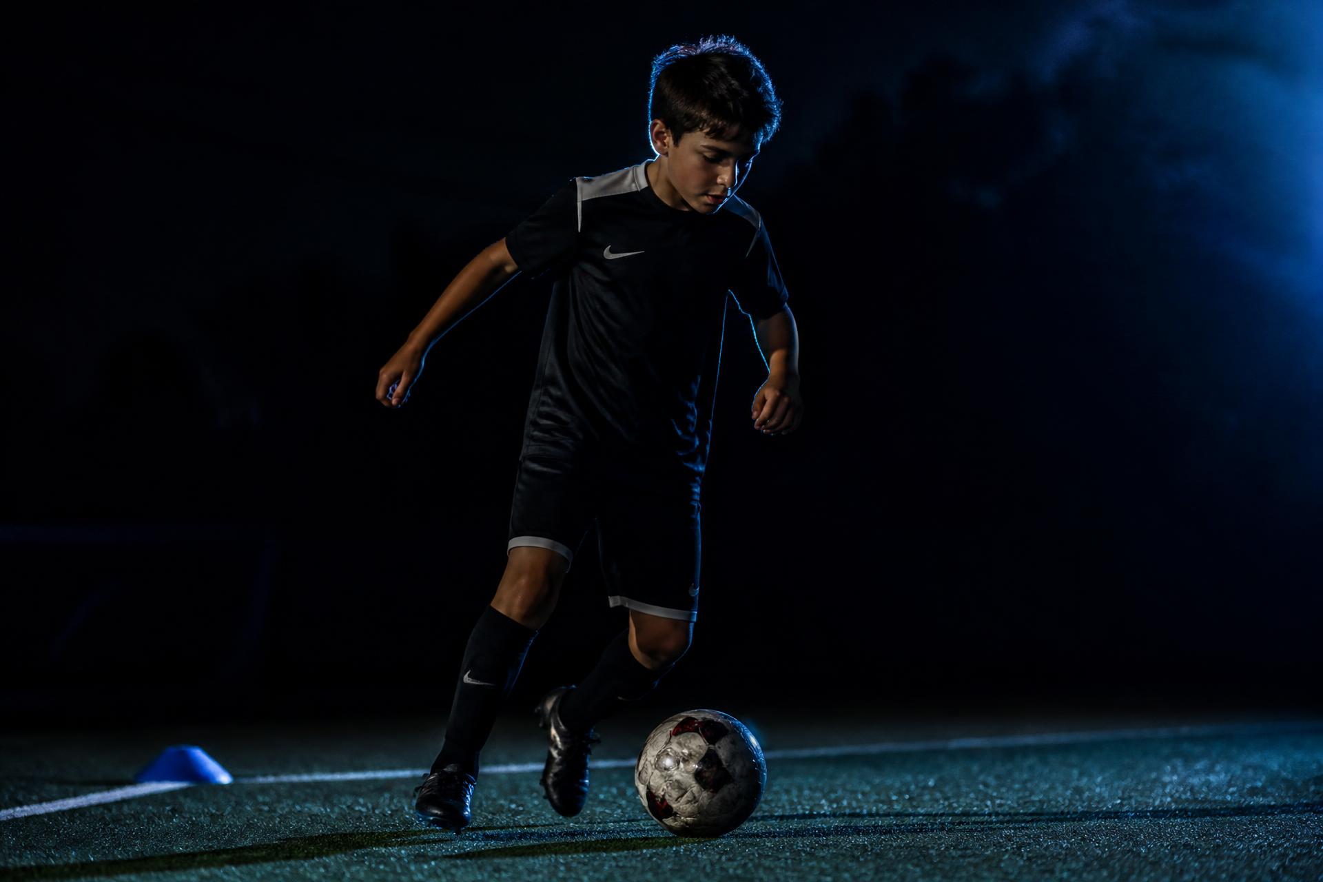 Youth soccer player training with a ball under floodlights